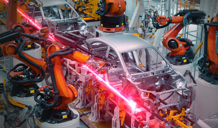 Robotic arms assembling a vehicle in a factory floor